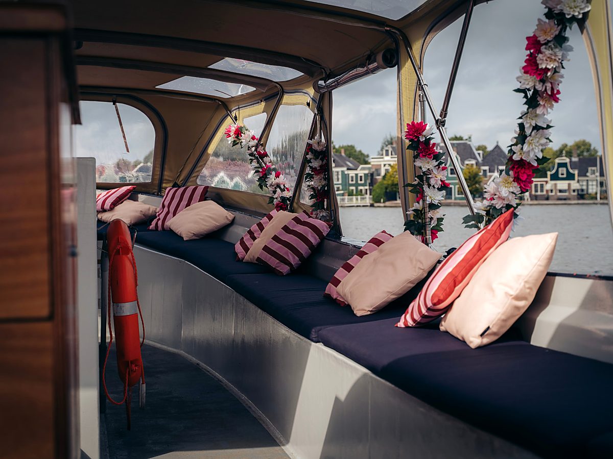 Het met kussens en bloemen versierde interieur van de sloep tijdens een vaart over de Amsterdamse wateren