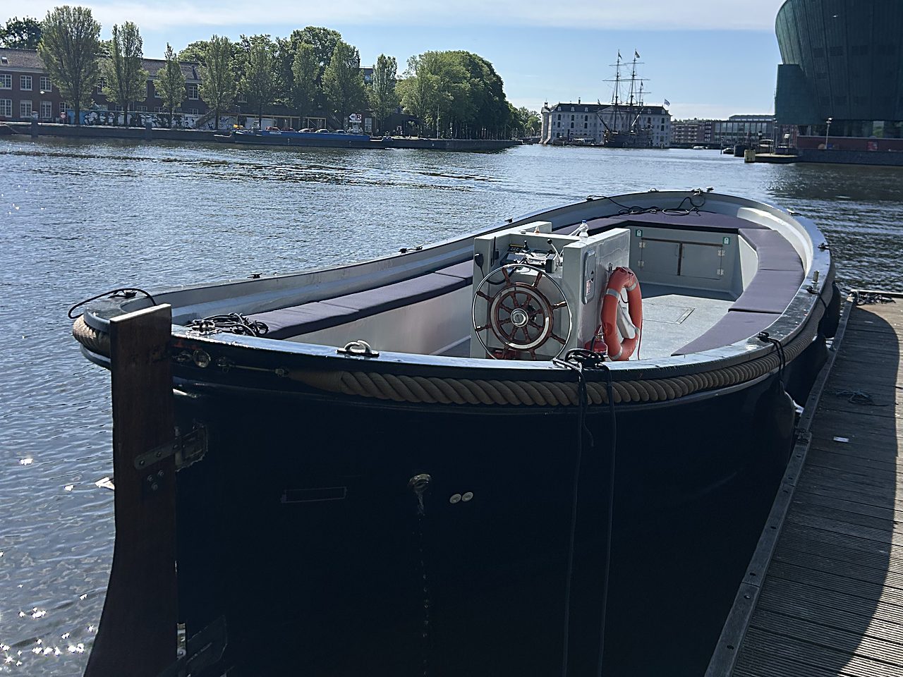Sloep Stelz ligt afgemeerd op het IJ met de Amsterdamse skyline