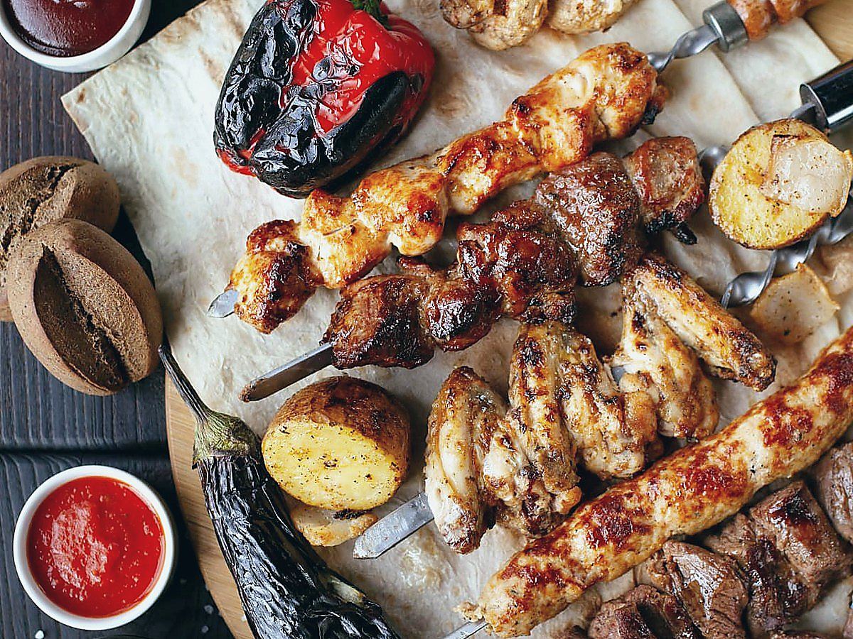 Gegrilde vleesspiezen, groenten en sausjes op platbrood, geserveerd aan boord